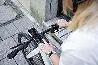 Fazua App V2.2 Update. Eine Person hält ihr Smartphone neben dem Fahrradlenker.