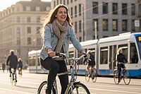 Eine Frau mit Jeansjacke und Schal fährt auf einem Fahrrad.