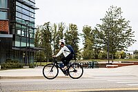 Frau auf Ebike vor Bürogebäude
