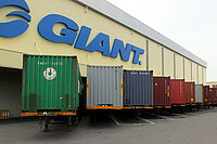 Lagerhalle mit Containern im Vordergrund. 