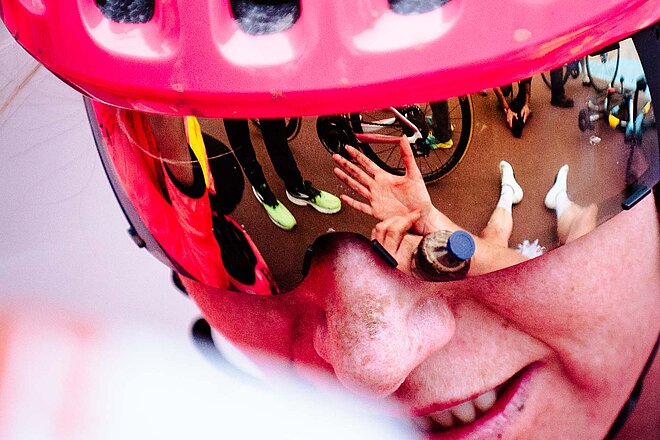 Gesicht einer Radrennfahrerin mit pinkem Helm.