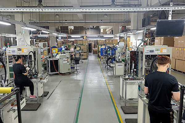 Warum sind die Lager der Velohändler voll. Arbeiterinnen und Arbeiter speichen Fahrradräder ein. 