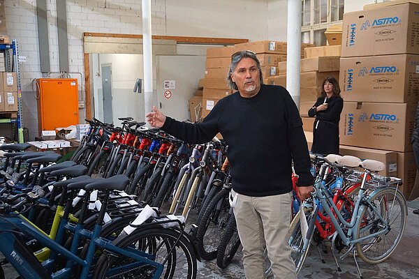 Ein Mann steht ein einem Lagerraum vor vielen Fahrrädern
