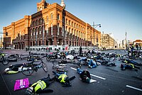 Menschen mit gelben Westen liegen auf einer Strasse am Boden. 