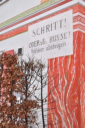 Aus der Bündner Autofeindlichkeit erwuchs nicht etwa die Förderung des Velotourismus, wie diese Drohung in Lavin zeigt. Radfahrer absteigen: Aufschrift an einer Hauswand.