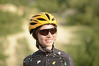 56 % der Schweizer tragen einen Velohelm. Eine Frau trägt einen gelben Fahrradhelm und eine Fahrradbrille. 