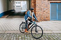 Alltagsfahrräder für weniger als 1600 Franken. Ein Mann radelt mit Jeansjacke und Helm. 