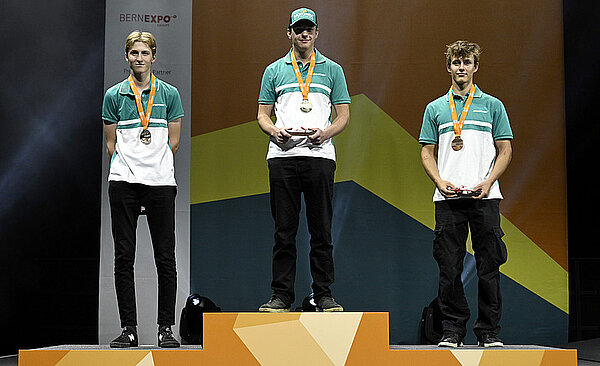 Die zentralen Berufsmeisterschaften SwissSkills 2022 bieten inspirierende Einblicke in die riesige Vielfalt an Schweizer Lehrberufen. Drei junge Männer stehen auf einem Podest.