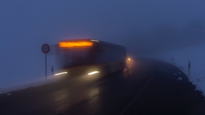 Ein Postauto fährt durch den Nebel.