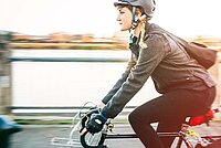 Die Cyclomania Velo-Challenge findet jährlich im September statt. Radfahrerin mit Jacke und Vintage-Rennrad fährt über eine Brücke.