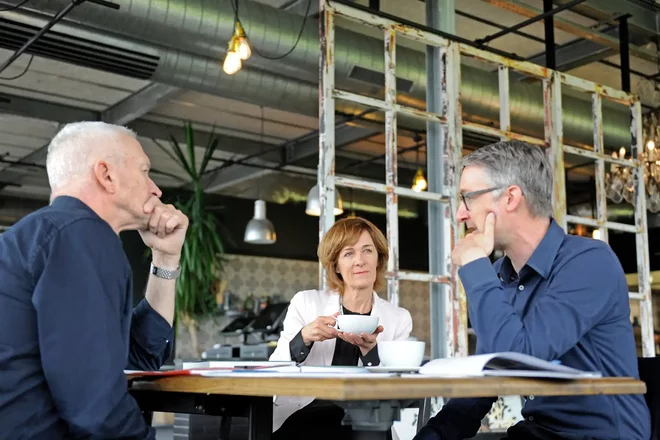Drei Personen sitzen an einem Tisch.