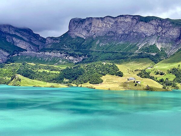 See mit türkis Wasser, im Hintergrund Berge.