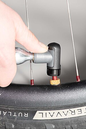 Eine Gaskartusche wird auf ein Fahrradventil gedrückt.