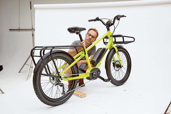 Benno Bikes Portrait. Eine Person kniet hinter einem Fahrrad in einem Fotostudio.