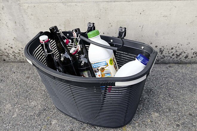 Korb gefüllt mit leeren Glasflaschen und Milchflaschen