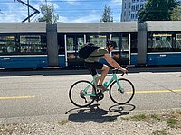 Velofahrer auf türkisem Velo vor Tram in Zürich