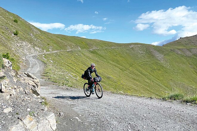 Die Assietta-Kamm-Strasse im Piemont ist ein Paradies für Gravelfans. Die Assietta-Kamm-Strasse im Piemont ist ein Paradies für Gravelfans. Ein Mann fährt auf einer Schotterstrasse mit dem Gravelbike.