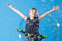 Spiele, die Kinder das Radfahren lehren. Ein Mädchen fängt Seifenblasen auf dem Fahrrad.