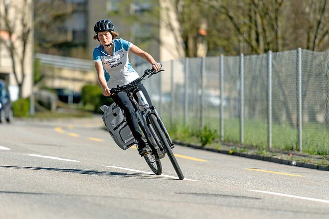 Fahrradtaschen Test. Eine Radfahrerin fährt eine Kurve auf der Strasse.
