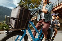 Longtailcargobike mit zwei Kindern in Kindersitzen auf dem Gepäckträger.