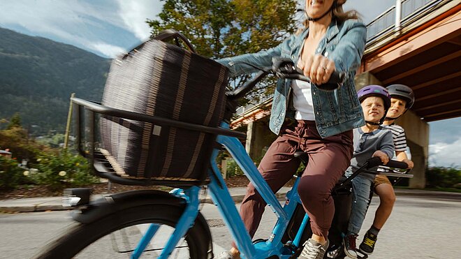 Longtailcargobike mit zwei Kindern in Kindersitzen auf dem Gepäckträger.