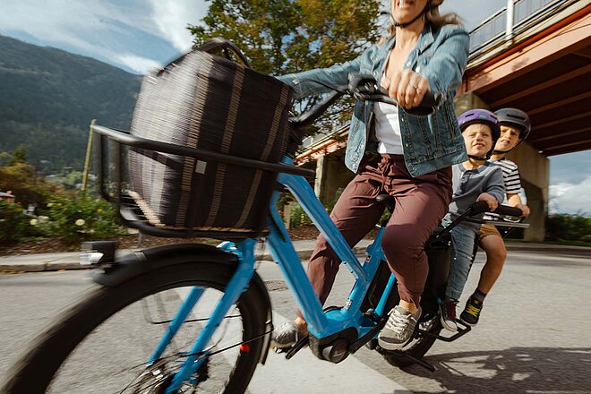 Longtailcargobike mit zwei Kindern in Kindersitzen auf dem Gepäckträger.