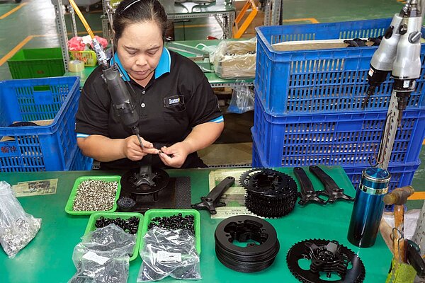 Eine Arbeiterin montiert Fahrradkurbeln in einer Fabrik.