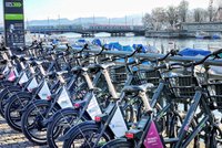 Viele Fahrräder stehen aufgereiht am Ufer eines Flusses