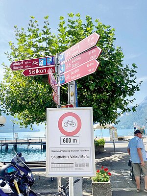 Velofahrverbot auf der Axenstrasse. Rote Wegweiser mit Fahrradrouten in der Schweiz.