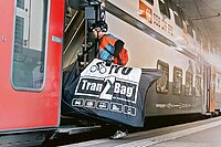 Velotransport in selbst genähten Tragetaschen nicht erlaubt. Ein Mann trägt sein Fahrrad in einer Tasche.