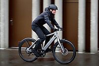 ZIV Studie Speed-Pedelecs. Ein Mann mit Regenbekleidung fährt auf einem E-Bike.