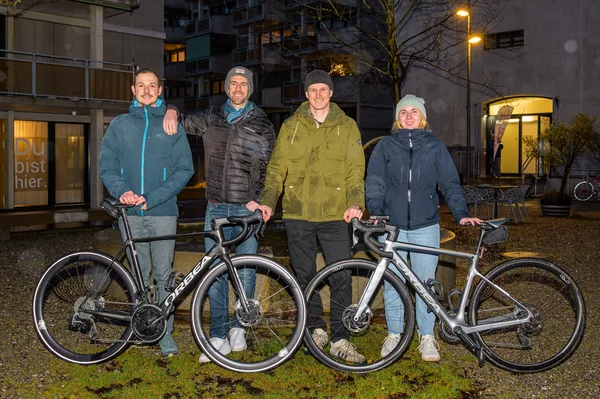 Vier Personen stehen mit Rennvelos auf einer Wiese.