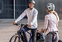 Veloplus Occasions E-Bikes. Ein Mann im weissen Hemd und mit Fahrradhelm sitzt auf einem E-Bike.