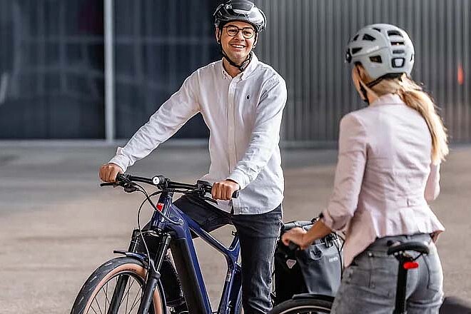 Mit dem Occasionsangebot verlängert Veloplus die Lebensdauer von E-Bikes der Mietveloflotte. Veloplus Occasions E-Bikes. Ein Mann im weissen Hemd und mit Fahrradhelm sitzt auf einem E-Bike.