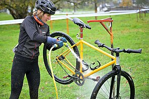 Eine Frau spritz ihr Fahrrad mit Wasser ab.