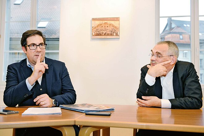 An einem Tisch:Christoph Niederberger (links) und Jean-François Steiert beim Gespräch im Amt für Raumplanung in Freiburg. Pro und Kontra Veloweggesetz. Zwei Männer im Anzug sitzen an einem Besprechungstisch..