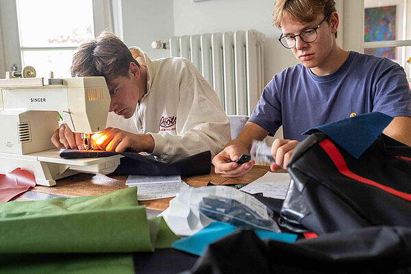 Zwei junge Männer nähen zu Hause Velotaschen. Es sind die Gründer von 2bag.