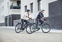 Zwei Personen auf einem E-Bike.