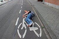 Mann liegt auf Fahrradspur