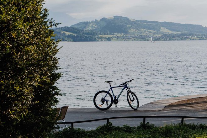 Richtplan Kanton Zug Alltags- Freizeitvelonetz. Ein Fahrrad steht an einem Seeufer. Auf der anderen Seiten des Sees ist ein Berg.