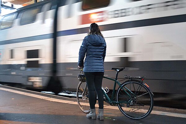 Frau mit Fahrrad auf dem Bahnsteig.