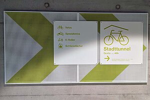 Schild, das Radfahrenden den Weg zu einem Veloparking weist. 
