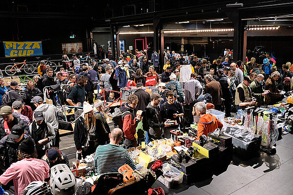 Velokultur in der Schweiz. Eine Halle voller Menschen, die an Ständen Fahrradteile und Zubehör kaufen.