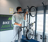 Mann hängt Velo an Velohaken trenitalia