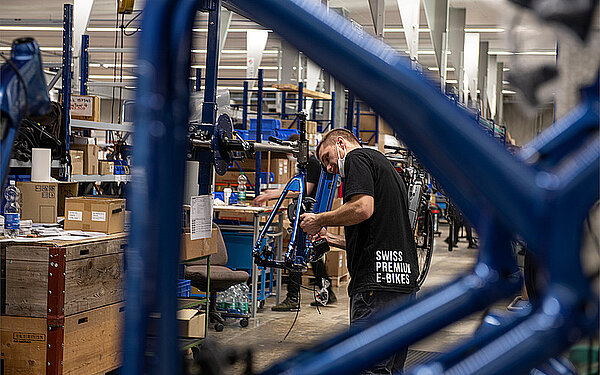 Flyer entlässt ein Drittel der Belegschaft. Ein Mann montiert ein E-Bike. 