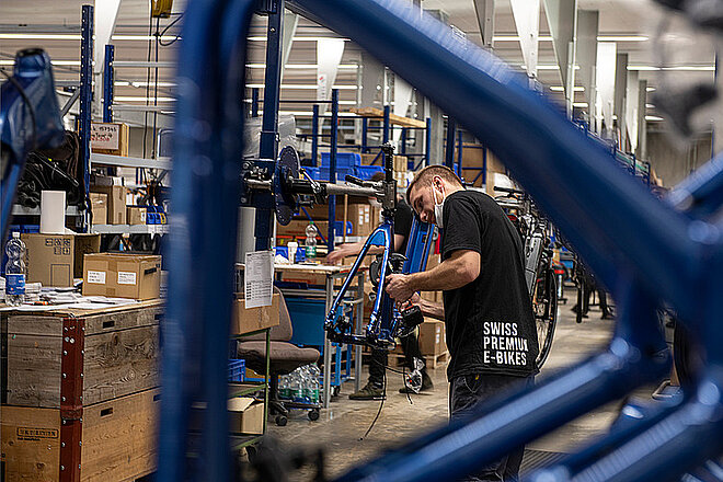 Wenn es bei den Bestellungen harzt, muss die Produktion gedrosselt werden. Und dann werden auch weniger Angestellte in der Fertigung gebraucht. Flyer entlässt ein Drittel der Belegschaft. Ein Mann montiert ein E-Bike.