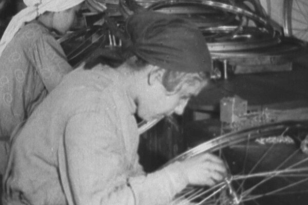 Die Geschichte des Radfahrens in der Ukraine. Schwarzweiss Foto einer Arbeiterin bei der Fahrradproduktion. 