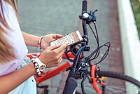 Vom 1. bis am 30. September geht die Cyclomania Velo-Challenge in die dritte Runde. Eine Frau hält ein Smartphone in der Hand.