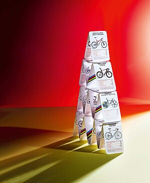 Ein Kartenhaus steht auf einer hell beleuchteten Fläche.