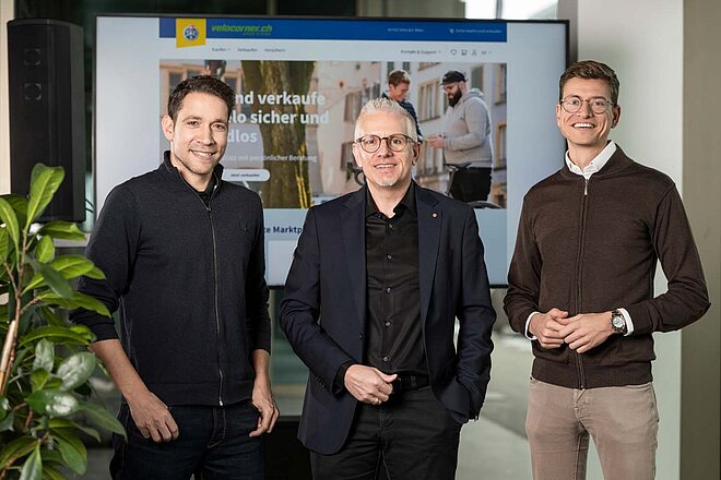 Die Velocorner-Gründer Mario Friedli (links) und Ciril Stebler (rechts) posieren mit Bernhard Bieri vom TCS. TCS übernimmt Velocorner. Drei Männer posieren für ein Foto.